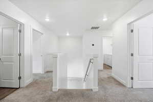 Hall featuring an upstairs landing, light colored carpet, recessed lighting, and washing machine and clothes dryer