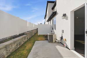 View of side of property featuring stucco siding, a fenced backyard, and a patio