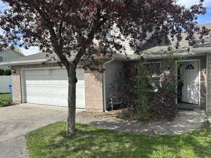 View of front facade featuring brick siding, driveway, a shingled roof, and an attached garage