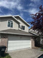 View of front of house with brick siding, a shingled roof, driveway, and an attached garage