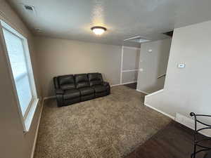 Living room with a textured ceiling and dark colored carpet