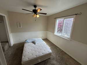 Bedroom with ceiling fan and dark colored carpet