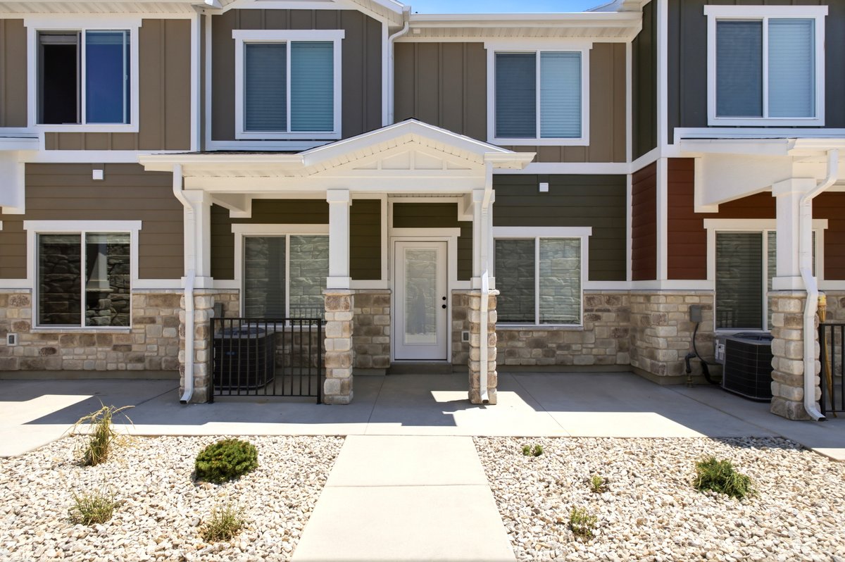 Multi-story residence featuring a covered entry, stone veneer accents, and a panel-style entry door with frosted glass