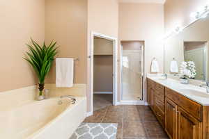 Bathroom featuring double vanity, a shower stall, a bath, and a spacious closet