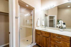 Bathroom with a walk in closet, vanity, a shower stall, and recessed lighting