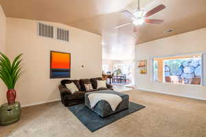 Living area featuring vaulted ceiling, carpet floors, ceiling fan, and suspended lighting