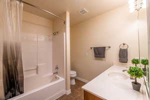 Bathroom with vanity, shower / bathtub combination with curtain, and dark tile patterned floors