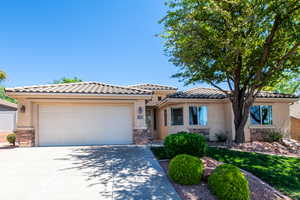 View of front facade with stone siding, driveway, a garage, stucco siding, and a tiled roof