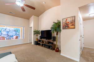Living room featuring light colored carpet, a ceiling fan, and vaulted ceiling
