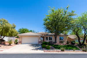 View of front of house with stone siding, an attached garage, driveway, a tile roof, and stucco siding
