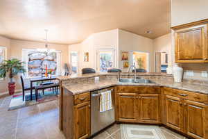 Kitchen with wood finish cabinets, dishwasher, a chandelier, and a peninsula