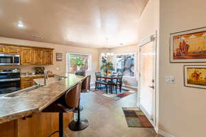 Kitchen featuring wood finish cabinetry, stainless steel appliances, a breakfast bar, a textured ceiling, and hanging lights