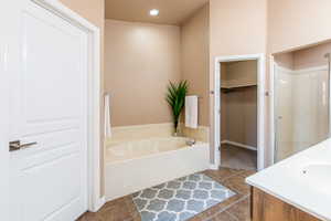 Full bath with a garden tub, vanity, a shower stall, a walk in closet, and recessed lighting