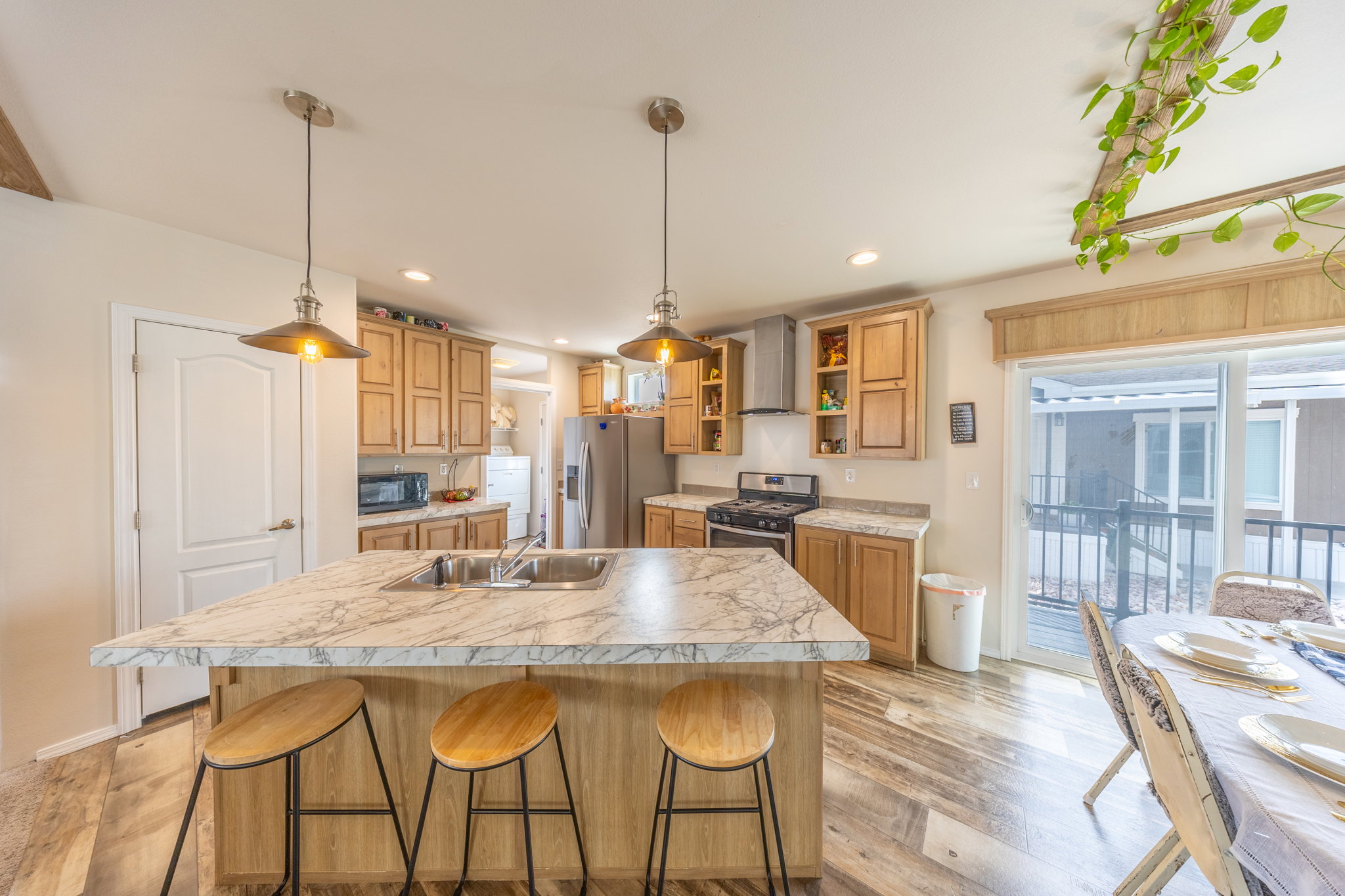 Kitchen featuring a kitchen bar, light countertops, stainless steel appliances, light wood-style flooring, and a center island with sink