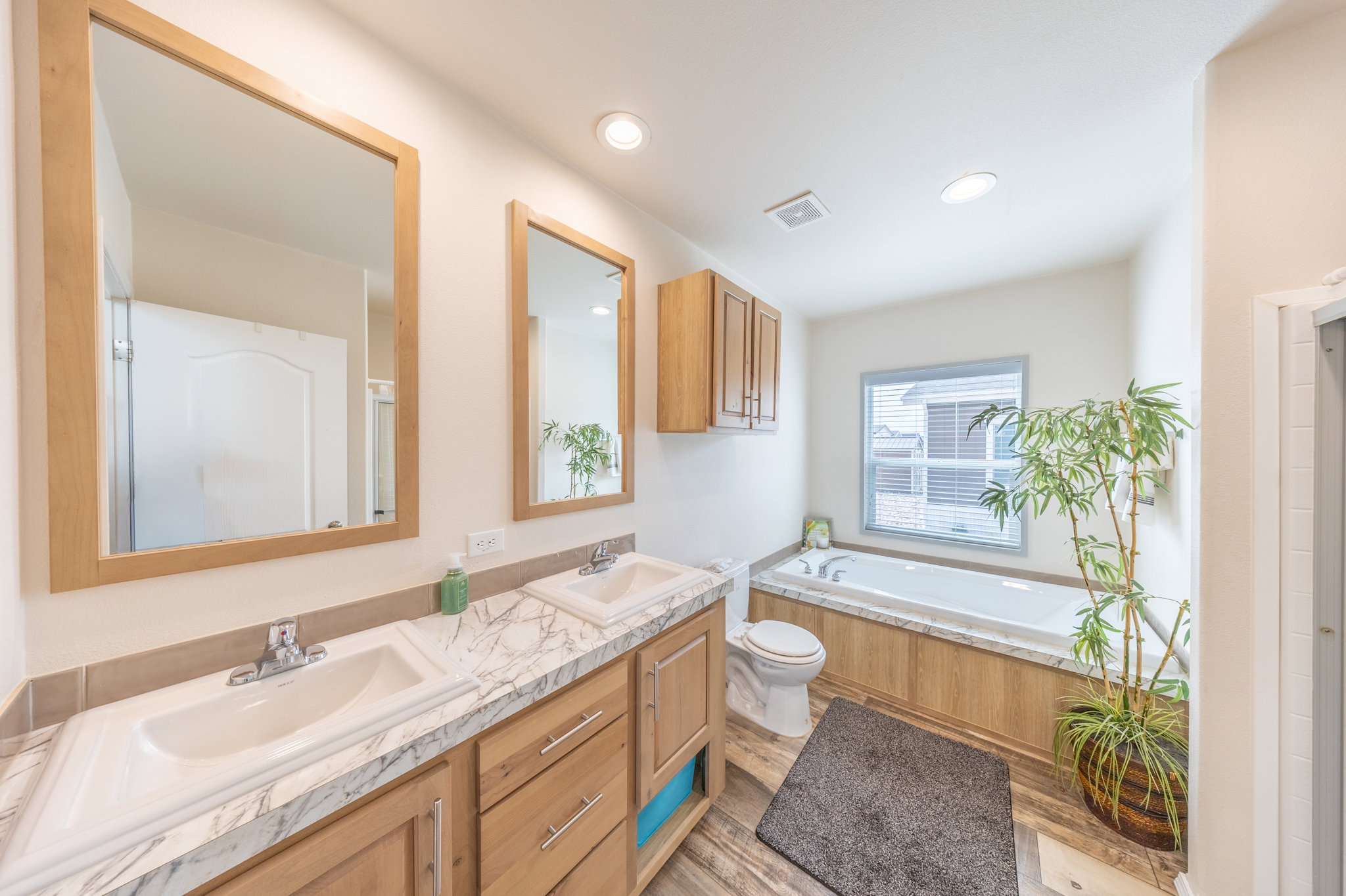 Full bathroom featuring a bath, double vanity, light wood-type flooring, and recessed lighting