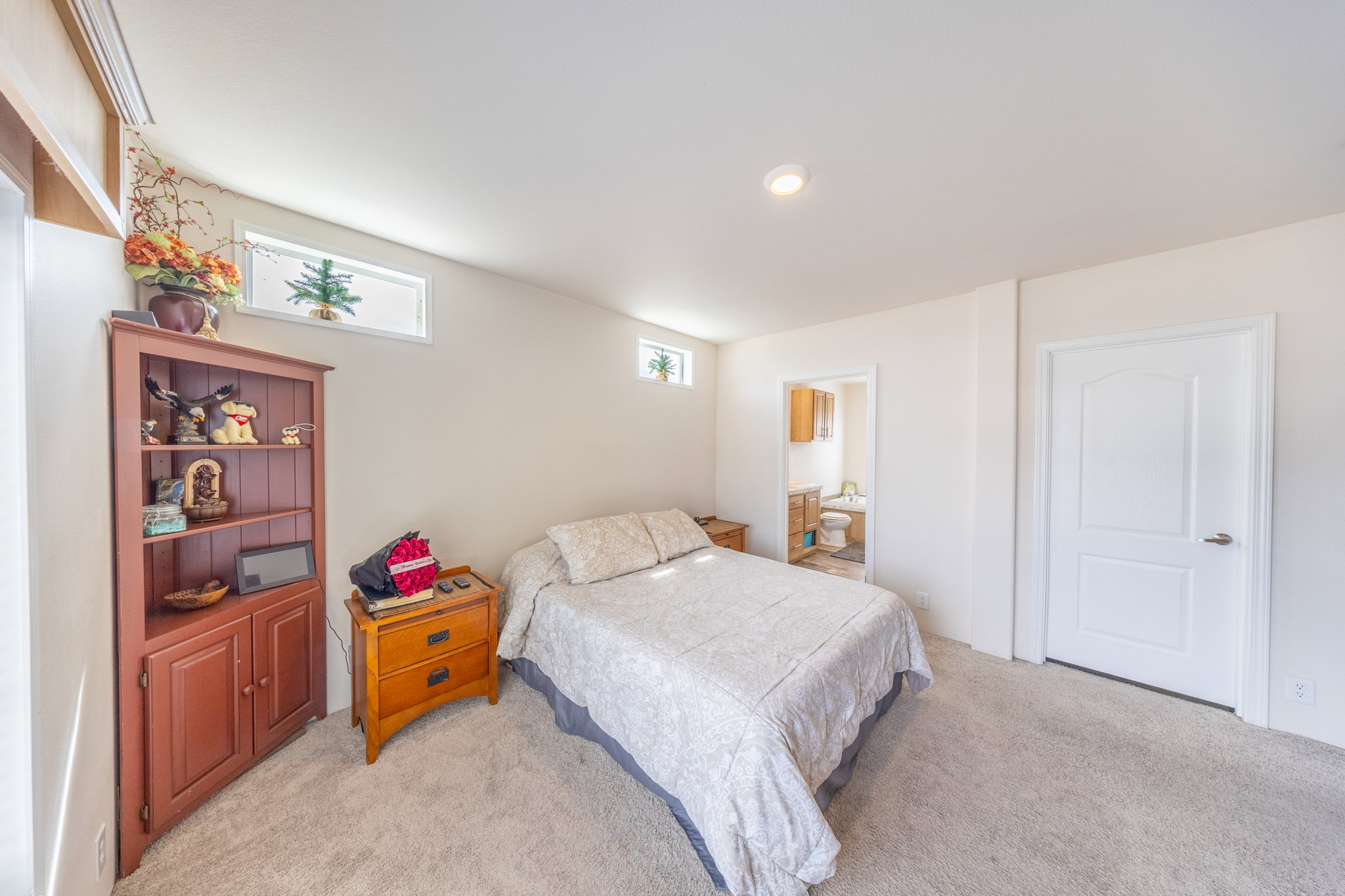 Primary Bedroom with ensuite bath and light colored carpet