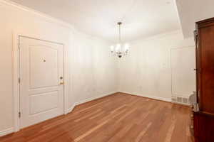 Unfurnished dining area featuring a chandelier, light wood-style flooring, ornamental molding, a textured ceiling, and electric panel