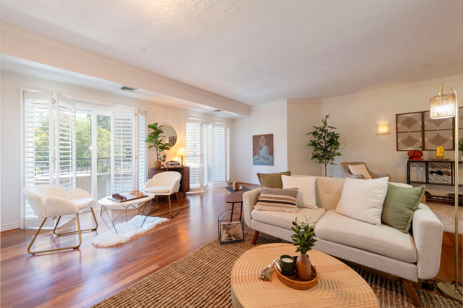 Spacious living area featuring polished wood-finish flooring and extensive crown molding