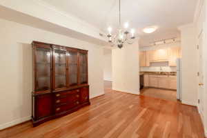 Unfurnished dining area featuring ornamental molding, suspended lighting, and light wood-style floors