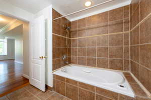 Full bathroom with a textured ceiling, tile patterned floors, and tiled shower / bath combo