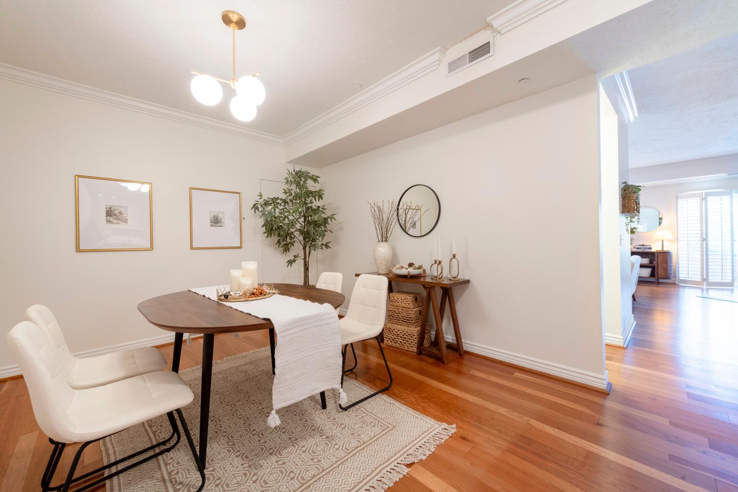 Dining area featuring warm wood-finish flooring and a contemporary brass chandelier