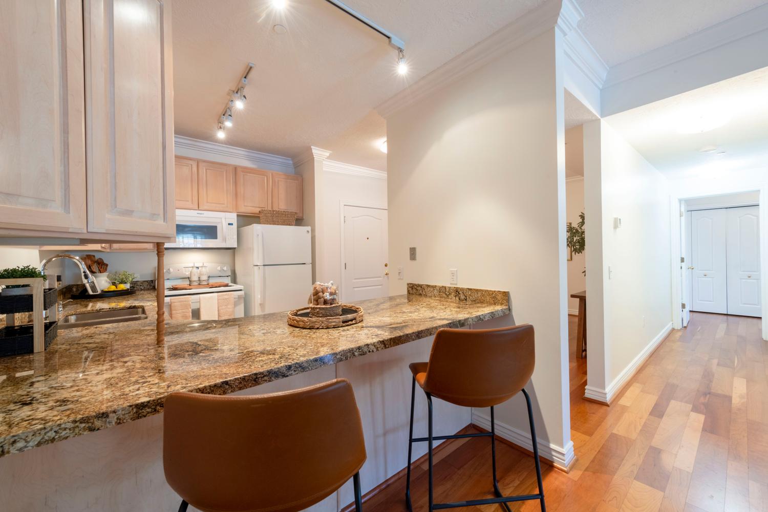 Kitchen with granite countertops, light wood cabinetry, and white appliances