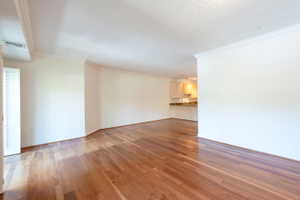 Empty room featuring crown molding and dark wood-type flooring