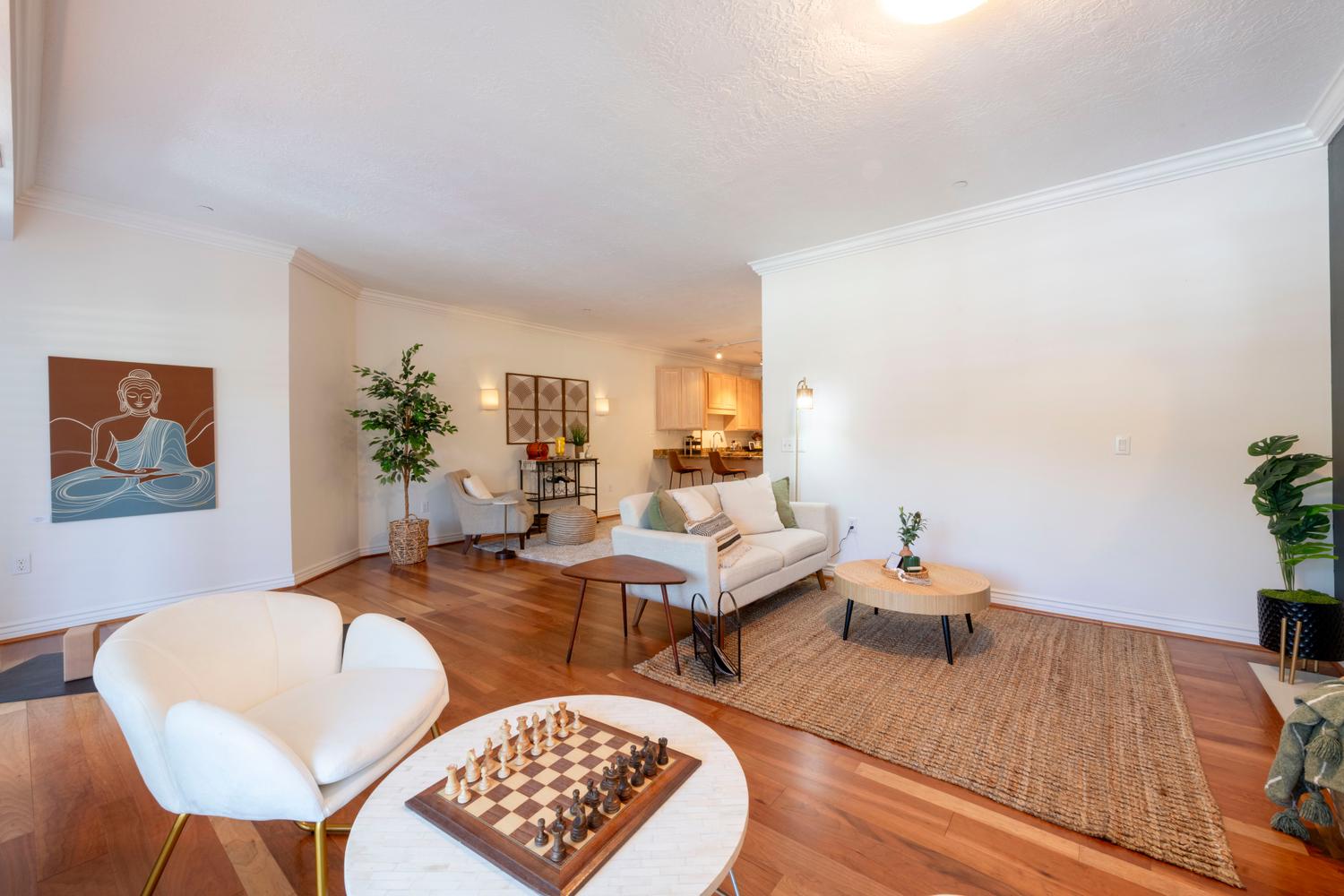 Spacious living area featuring wood-finish flooring, white crown molding, and a neutral color palette