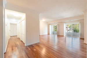 Empty room featuring light wood finished floors, crown molding, and a textured ceiling