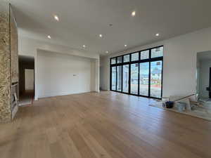 Unfurnished living room with light wood finished floors, recessed lighting, and a stone fireplace