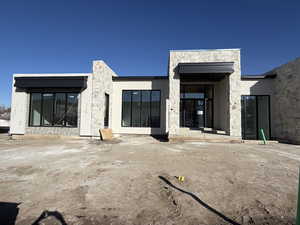 Rear view of house featuring stone siding, a patio, and stucco siding