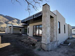 Back of property with stucco siding, a mountain view, a patio, and stone siding