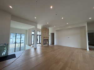 Unfurnished living room featuring a multi sided fireplace, light wood finished floors, and recessed lighting