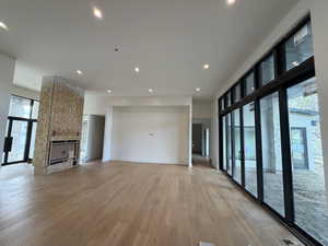 Unfurnished living room featuring a fireplace, healthy amount of natural light, light wood-style flooring, and recessed lighting
