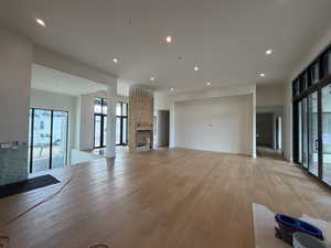 Unfurnished living room featuring light wood-style flooring, recessed lighting, and a stone fireplace