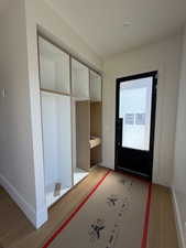 Doorway to outside with wood finished floors and baseboards