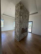Unfurnished living room featuring a fireplace, a raised ceiling, wood-type flooring, and plenty of natural light