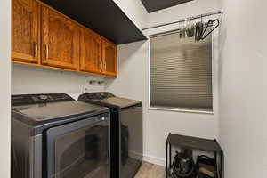 Laundry area featuring washer and dryer, light wood-style flooring, and cabinet space