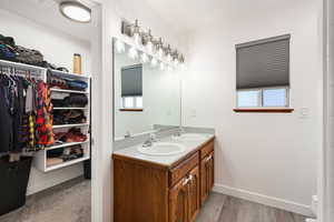 Bathroom featuring double vanity, a walk in closet, and light wood-style floors