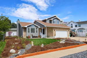 View of front of home featuring driveway, brick siding, roof with shingles, an attached garage, and a chimney