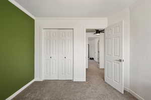 Unfurnished bedroom featuring light carpet, crown molding, and a closet