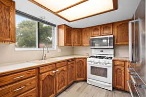 Kitchen with light countertops, stainless steel appliances, wood finish cabinetry, and light wood finished floors