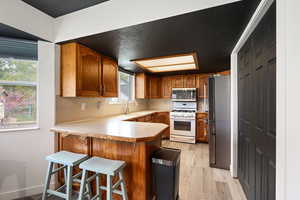Kitchen with wood finish cabinets, light countertops, a breakfast bar area, stainless steel appliances, and a peninsula