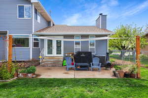 Back of house with entry steps, roof with shingles, a chimney, and a patio area