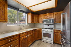 Kitchen with stainless steel appliances, light countertops, wood finish cabinetry, and light wood-style flooring