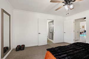 Bedroom featuring light carpet, crown molding, ensuite bathroom, and a ceiling fan