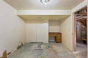 Unfurnished bedroom featuring a closet, a textured ceiling, and built in desk