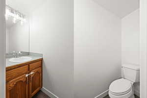 Half bathroom with vanity, lofted ceiling, and dark wood-style flooring