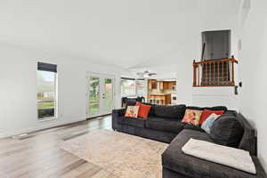 Living room featuring french doors, plenty of natural light, lofted ceiling, ceiling fan, and light wood-style floors