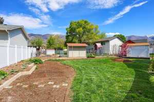 Fenced backyard with a mountain view, a storage unit, and a garden